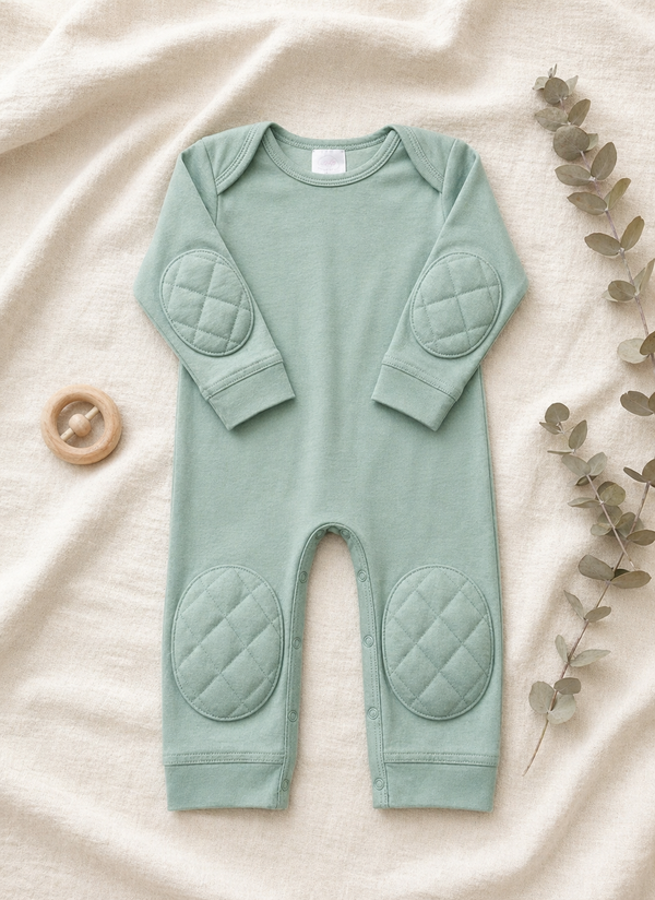 Green Tea padded onesie flat lay on cream linen with eucalyptus branch and wooden teething ring - front view