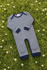 Navy Stripe padded onesie on spring grass with daisies - front view of narrow navy and cream stripes