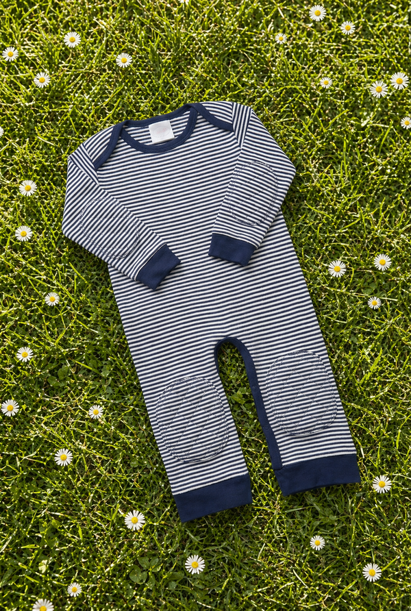 Navy Stripe padded onesie on spring grass with daisies - front view of narrow navy and cream stripes