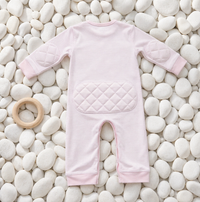 Pink Stripe padded onesie on white river pebbles with wooden teething ring - back view