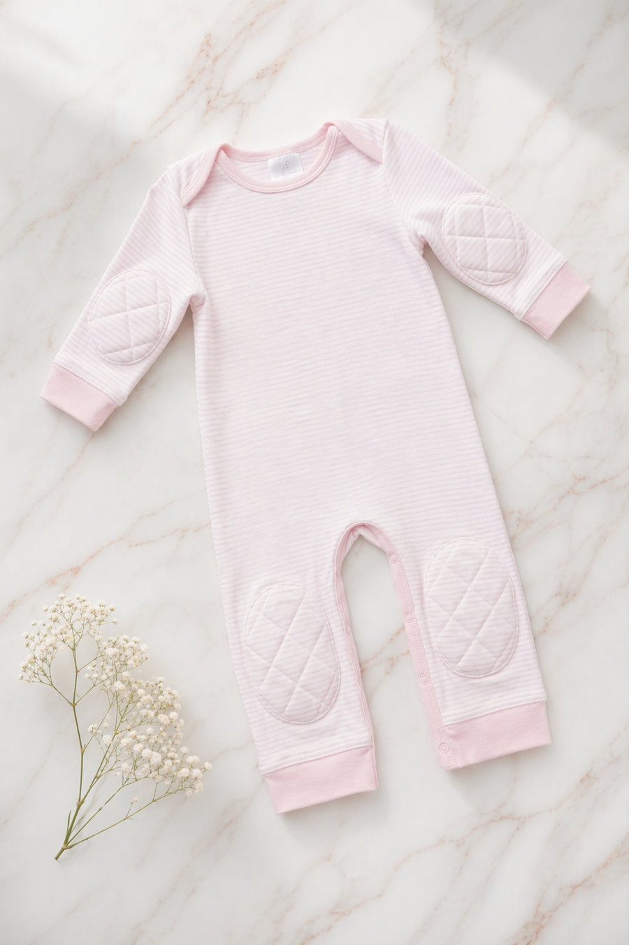 Pink Stripe padded onesie on white marble with baby's breath - front view of narrow pink and cream stripes